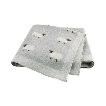 Couverture bébé grise en coton à motifs moutons, pliée sur fond blanc