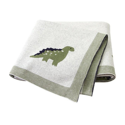 Couverture bébé verte en coton à motifs dinosaures, pliée sur fond blanc