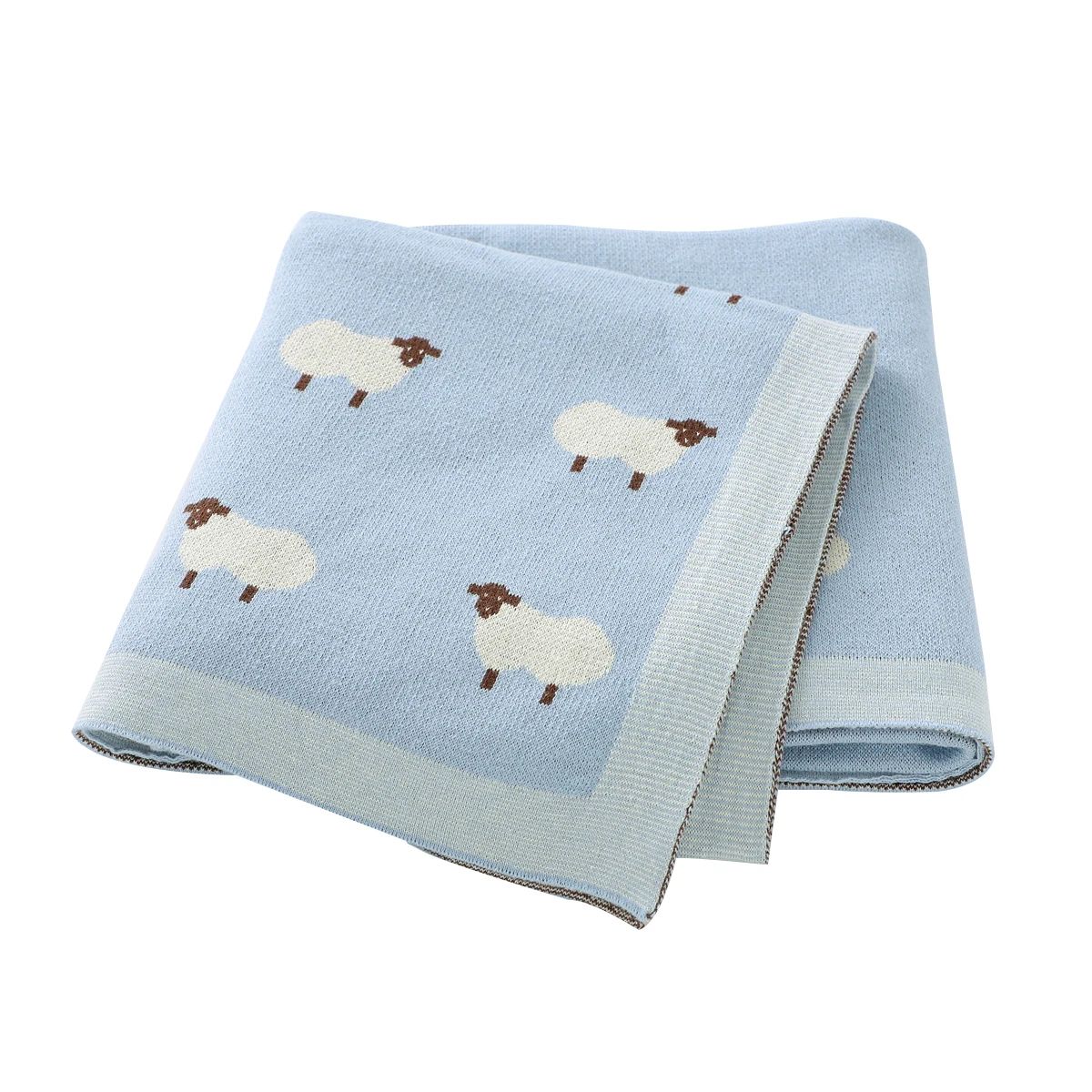 Couverture bébé bleue en coton à motifs moutons, pliée sur fond blanc