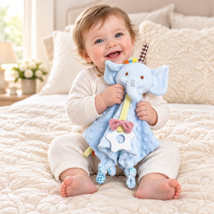 Bébé assis sur le lit, souriant, tenant le doudou éléphant
