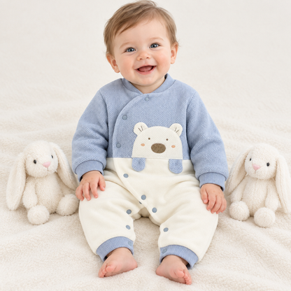 Bébé garçon assis entre deux lapins en peluche, pyjama bleu ourson