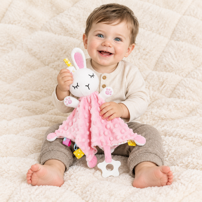 Bébé garçon souriant naturellement, assis avec le doudou, tissu texturé