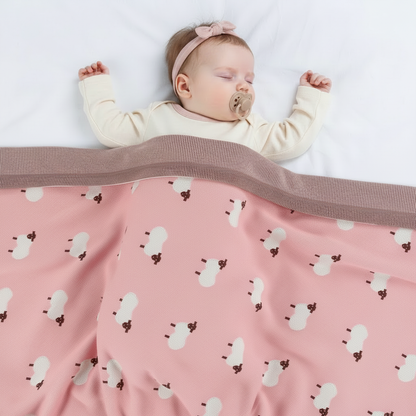 Petite fille avec la couverture rose à motifs moutons